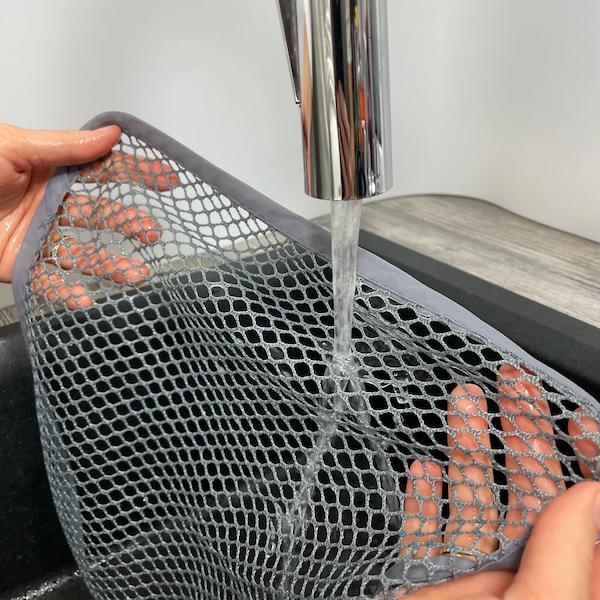 Reinigungstuch wird unter fließendem Wasser abgespült